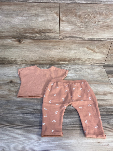 Peach baby outfit set with short sleeve top and rainbow print pants on wood background