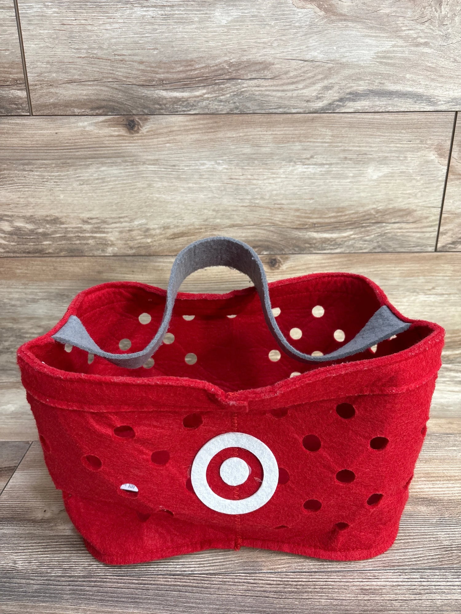 Red polka dot felt basket with white bullseye logo, gray handle, on wood floor