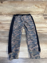 Kids camo jogger pants with black side panels on rustic wood background
