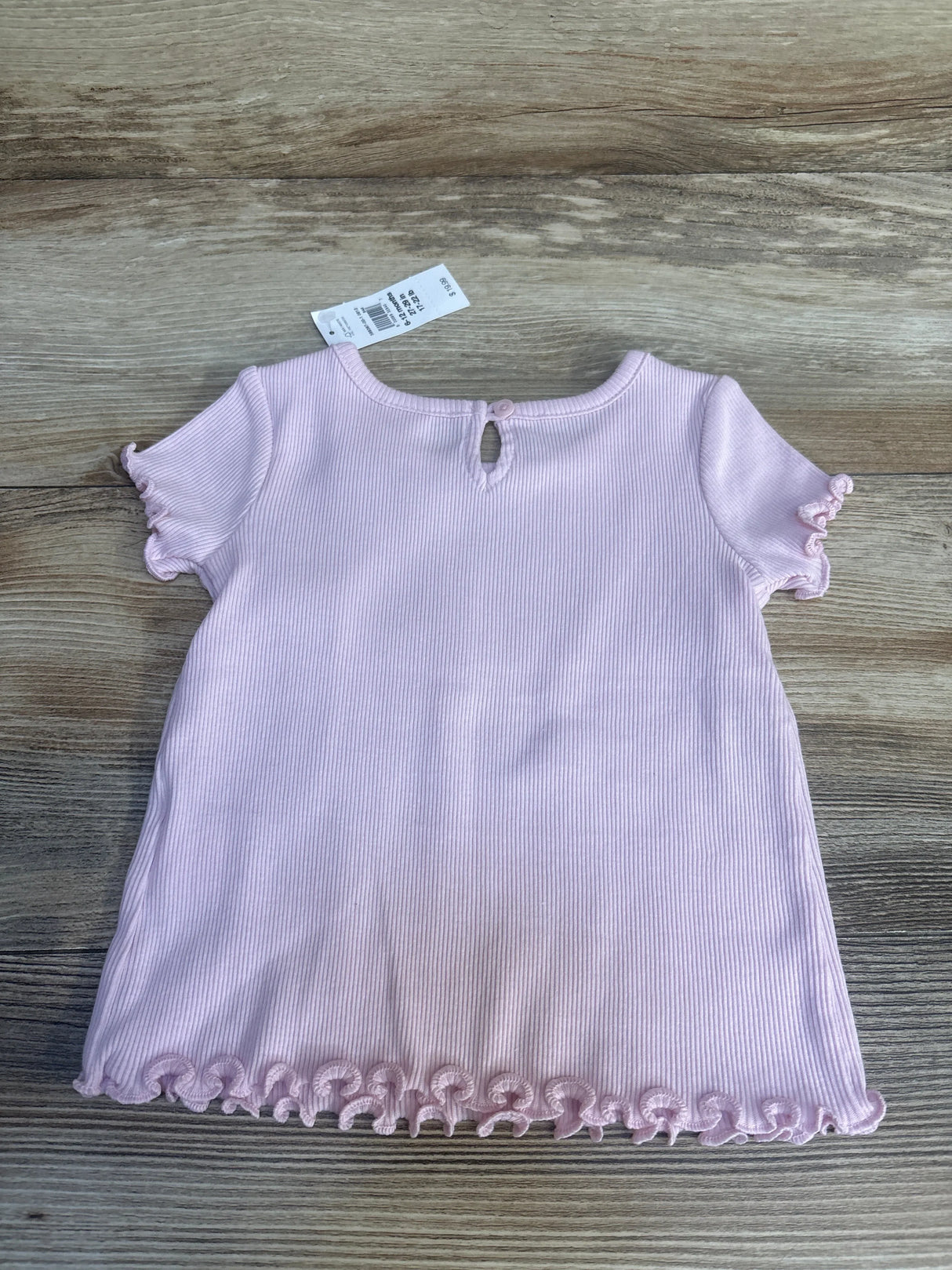 Back view of Baby Gap ribbed lettuce-trim baby shirt showing keyhole button, ruffled sleeves, and lettuce hem on wood background