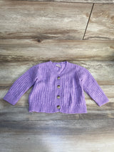 Purple knit baby cardigan with buttons on wood background