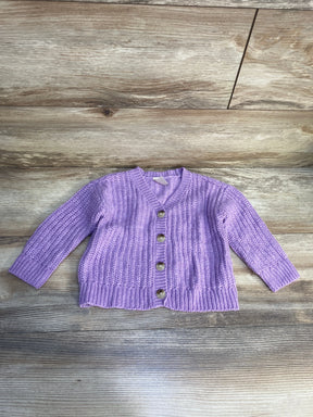 Purple knit baby cardigan with buttons on wood background