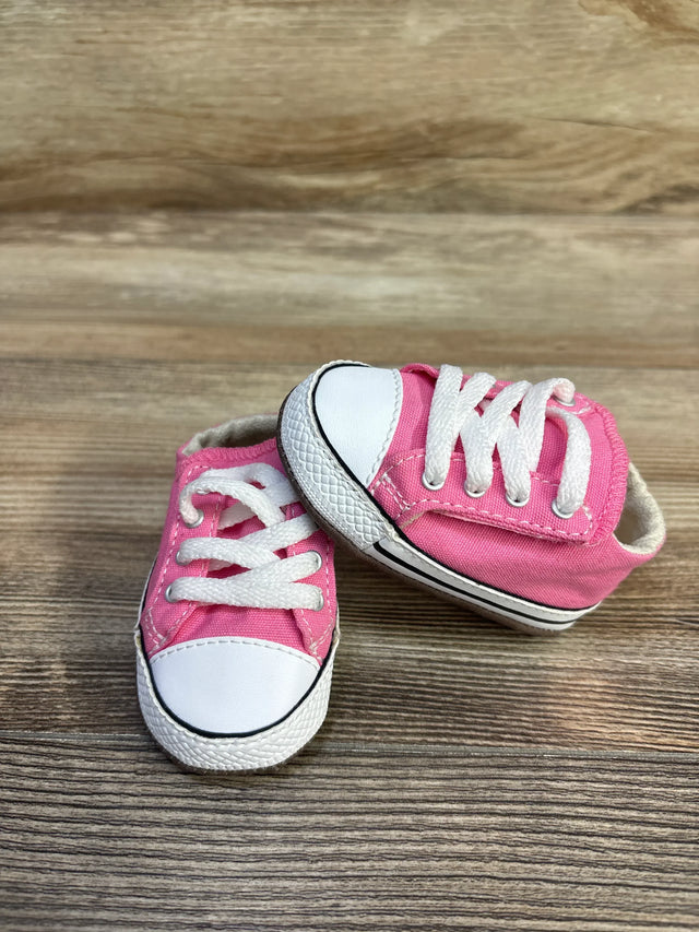 Front three-quarter view of Converse Cribster baby shoes, pink canvas with white toe caps and laces on wood background