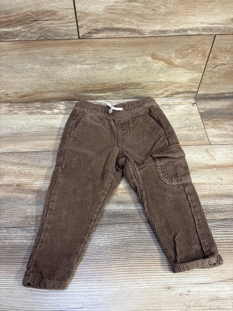 Flat lay of brown corduroy pants size 12-18m showing elastic drawstring waist and cargo pocket on wood floor