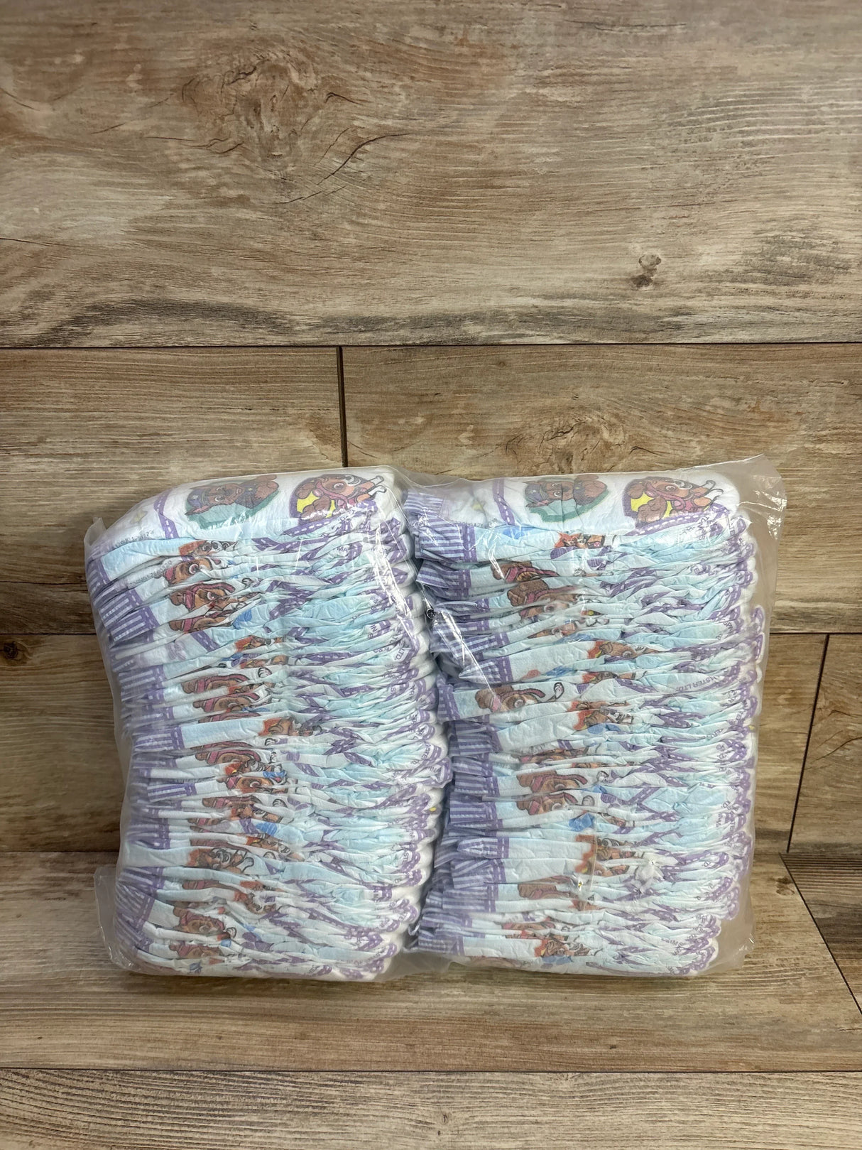Front view of a sleeve of 80 Luvs Paw Patrol size 2 diapers showcasing character print on a wood background