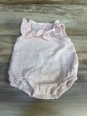 Flat lay of pink floral bubble romper showcasing ruffle collar, textured gauze fabric, and snap crotch closures on wood-grain background