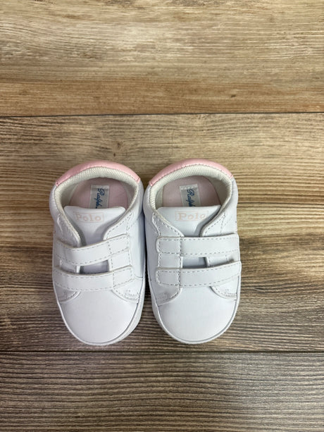 Top view of white Polo Ralph Lauren Heritage Court II EZ crib sneakers showcasing dual hook-and-loop straps and pink lining on a wood surface