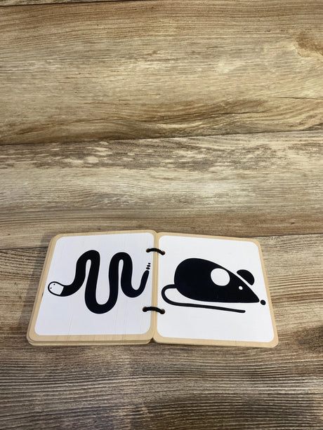 Front view of Lovevery wooden board book open to black snake and mouse illustrations on white pages on a wood tabletop