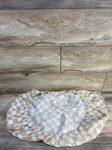 Top-down view of Brixton Phoenix muslin bassinet sheet with beige-and-white check and elastic fitted edge on wood background