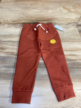 Rust colored toddler jogger pants with front pocket and drawstring, displayed on wood floor