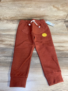 Rust colored toddler jogger pants with front pocket and drawstring, displayed on wood floor