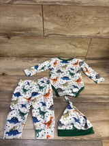Flat lay of white three-piece dinosaur set with long-sleeve bodysuit, pants, and hat featuring multicolor dinosaur print
