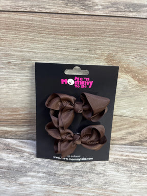 Front view of two brown grosgrain ribbon hair bows 2 pack on a black Me n Mommy To Be card against a wood background
