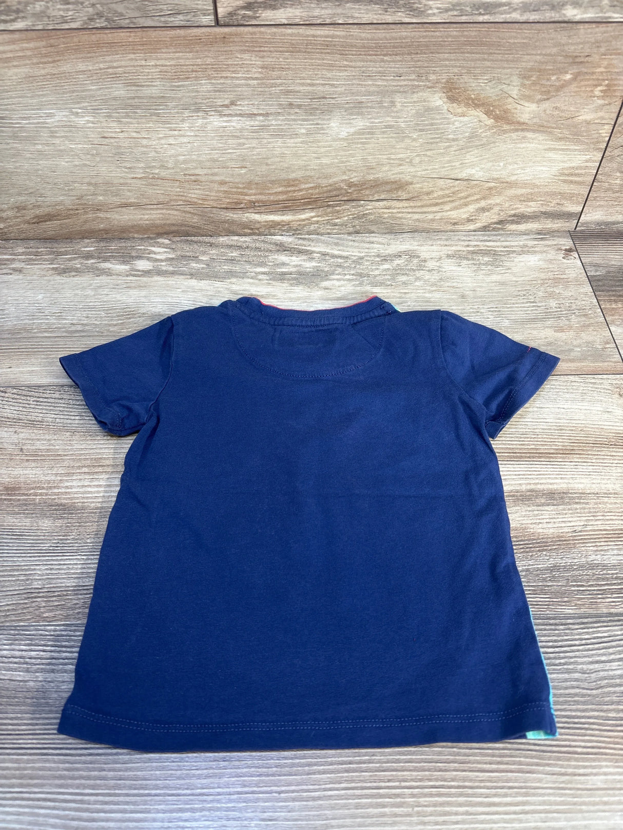 Navy blue short sleeve kids t-shirt laid flat on wood background