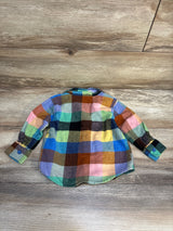 Colorful plaid flannel long sleeve toddler shirt laid flat on wood floor