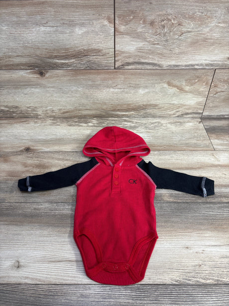 Red baby hooded bodysuit with black long sleeves, snap closure, and CK logo on wood floor
