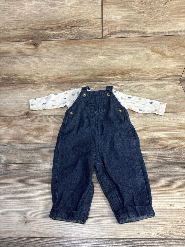 Flat lay of ivory long-sleeve top and dark denim overalls, size 3M, showing button straps and snap closures on wood background