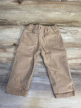 Back view of tan toddler pants with elastic waistband and two back pockets on wood surface