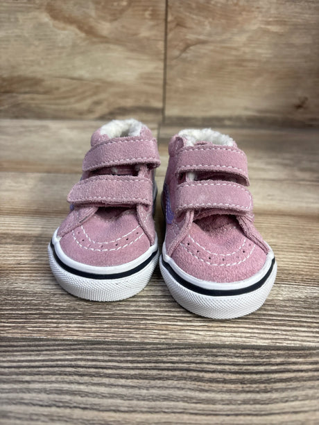 Front view of Vans SK8-Mid Reissue V sneakers in pink with two hook-and-loop straps, fuzzy lining, and white soles on a wood surface