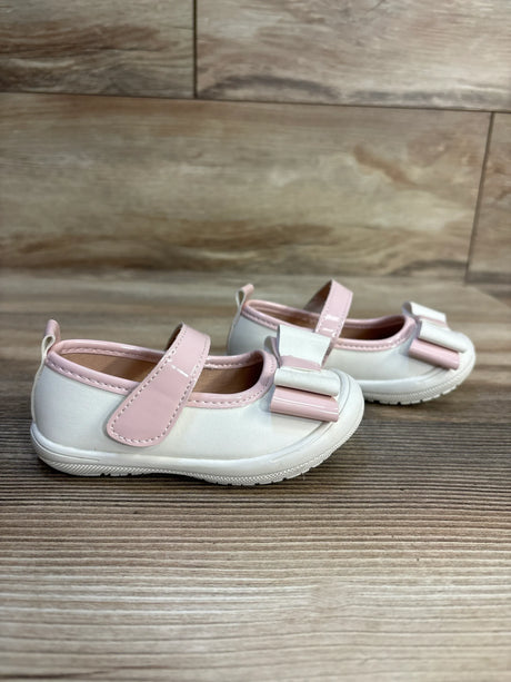 Pink and white toddler Mary Jane shoes with bows on wooden floor