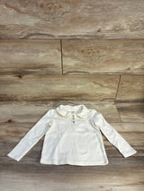 Flat lay of cream Gymboree long-sleeve Peter Pan collar top with ruffle collar and three buttons on wood floor, size 3T