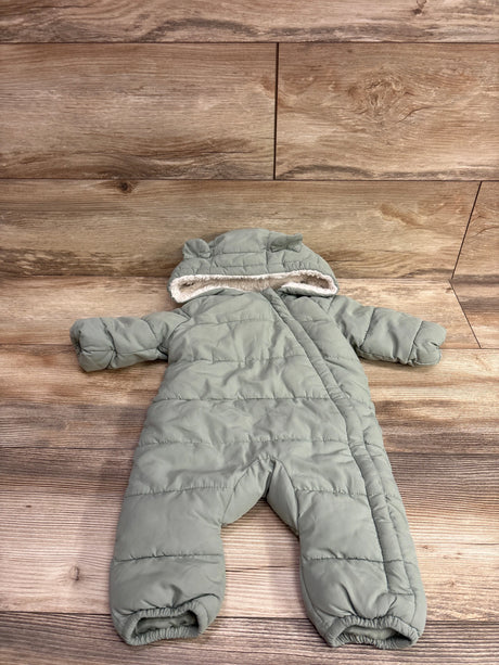 Top view of green fur-lined bunting for 1 to 3 months showcasing hood and quilted padding on a wood floor