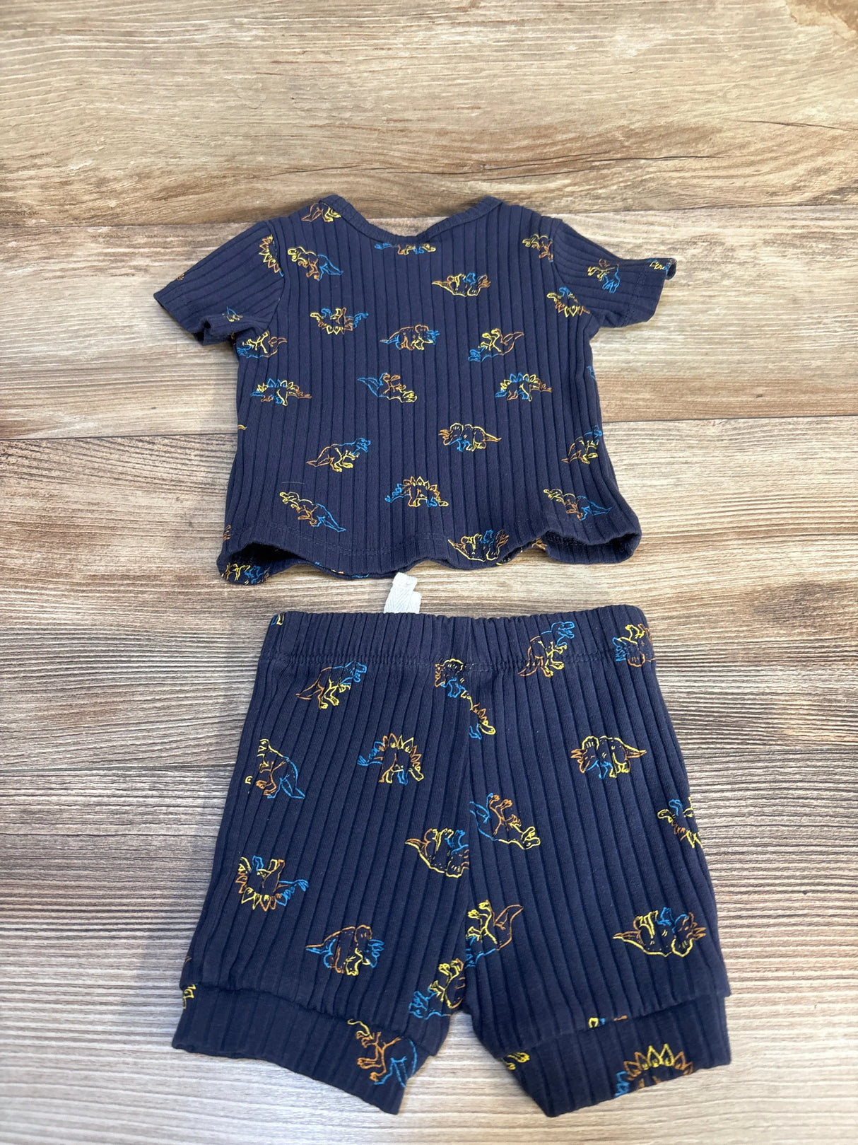 Navy blue ribbed toddler shirt and shorts set with colorful dinosaur print on wood background