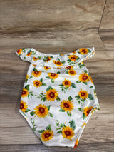 Flat lay of white off-shoulder baby romper showcasing sunflower print and ruffle trim, size 12 months, on wood floor