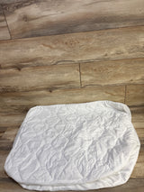 Top down view of Amfori waterproof crib mattress protector showing quilted top and elastic skirt on wood floor