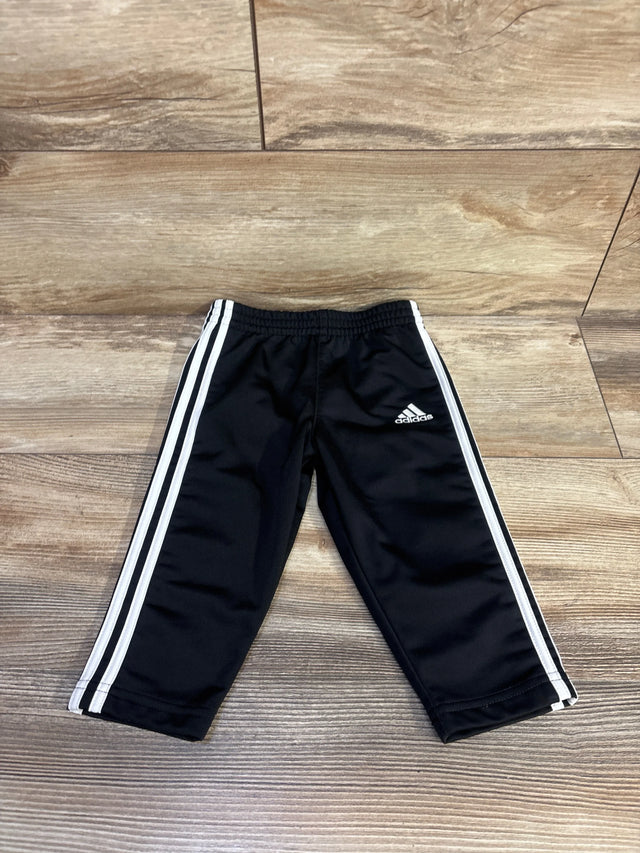 Front flat lay of black Adidas track pants size 12 months showing elastic waistband, white side stripes and logo on wood floor
