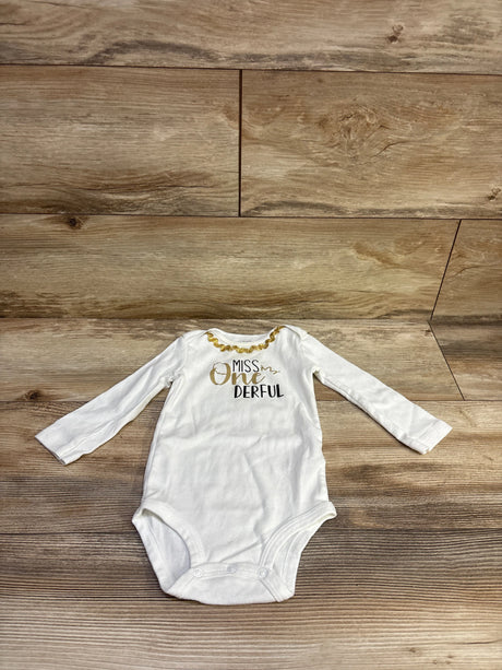 Front view of Carter’s Miss One Derful white 12m bodysuit with long sleeves, gold trim, and snap closure on wood