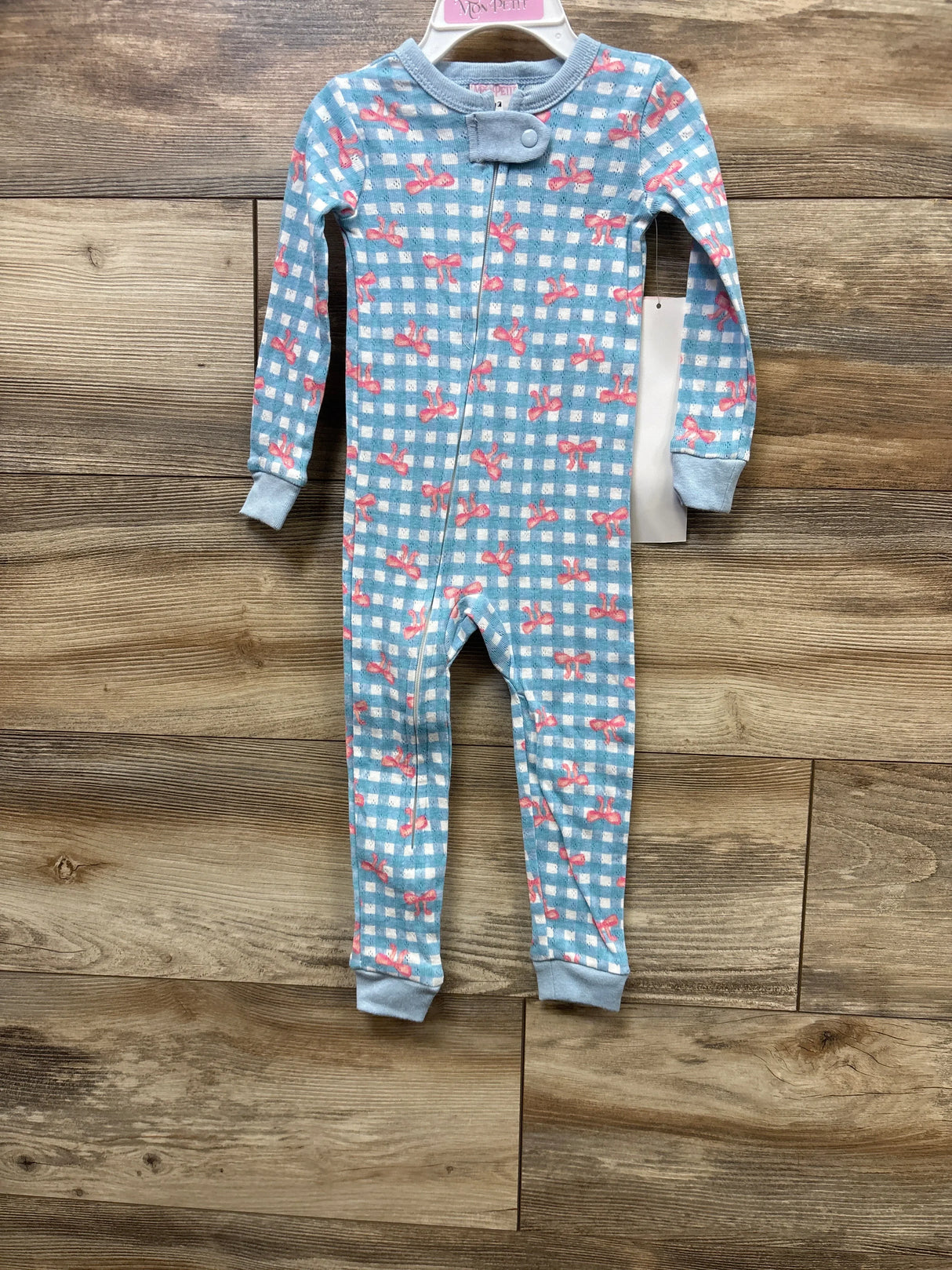 Blue gingham baby onesie with pink bows, long sleeves, front zipper, on wooden floor