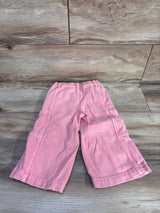 Flat lay of pink Baby Gap baggy cargo toddler jeans showcasing elastic waistband and side cargo pockets on wood floor backdrop