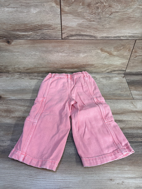 Flat lay of pink Baby Gap baggy cargo toddler jeans showcasing elastic waistband and side cargo pockets on wood floor backdrop