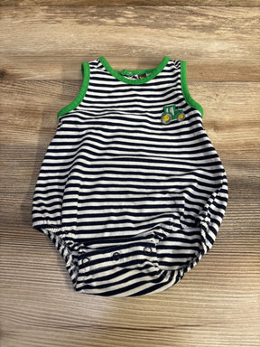 Flat lay of navy and white striped baby romper showcasing green trim, small tractor patch, and three snap crotch closures on wood surface