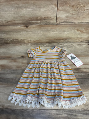 Striped baby dress with ruffled sleeves and white lace hem on wooden floor