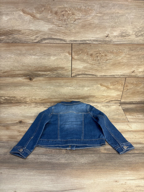 Back view of a children's blue denim jacket on wood floor background