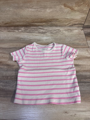 Flat lay of H&M ribbed short-sleeve toddler shirt with white and pink horizontal stripes and ruffled sleeve edges on wood background