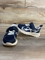 Navy blue and white toddler sneakers with velcro straps on wood background
