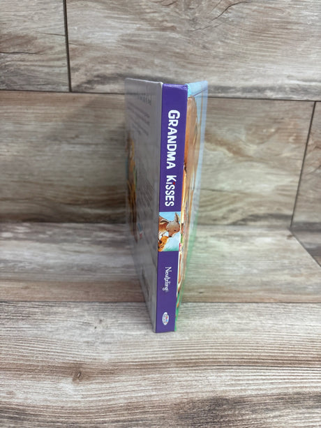 Side view of Grandma Kisses board book showcasing its purple spine on a wood surface