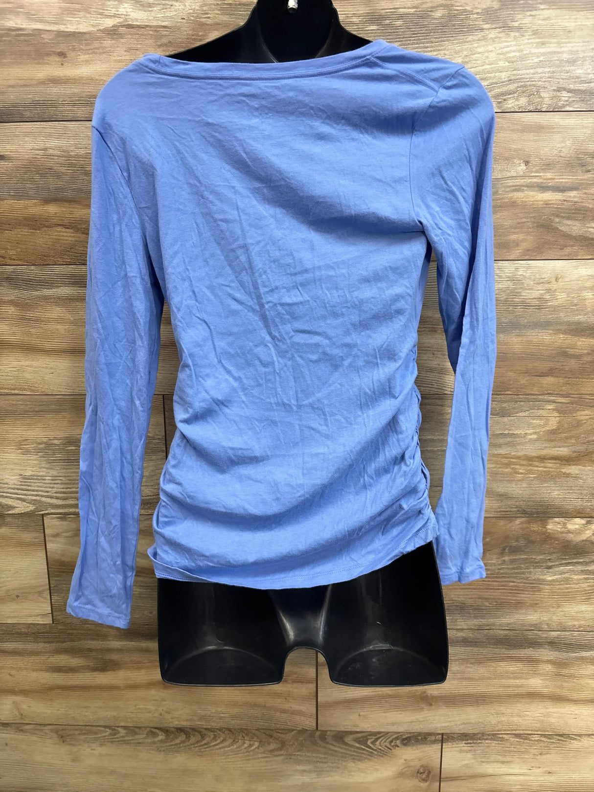 Back view of blue Isabel maternity long-sleeve shirt, size M, showing side ruching on a black mannequin against wood backdrop