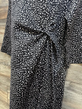 Front close up of Hatch Maternity Lauren dress showing side twist knot and black speckled print on wood background