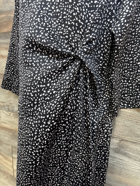 Front close up of Hatch Maternity Lauren dress showing side twist knot and black speckled print on wood background
