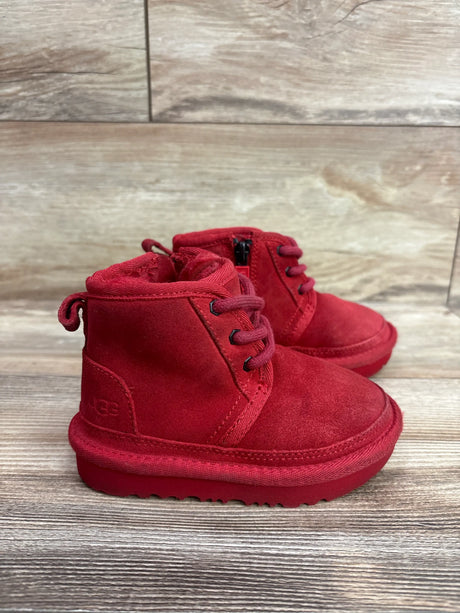 Front three-quarter view of red UGG Neumel II boots showcasing lace-up fronts and side zippers with a wood-patterned background