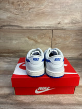 Rear view of Nike Dunk Low TD toddler sneakers with white leather, Hyper Royal heel logo and blue soles on red Nike box