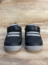Black and gray toddler sneakers with velcro straps on wooden background