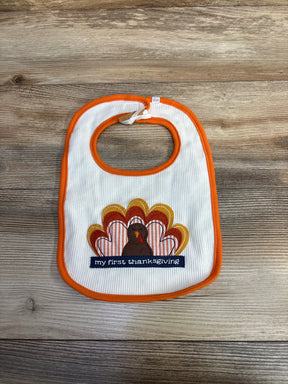 Baby bib with turkey and 'my first thanksgiving' text on wood background