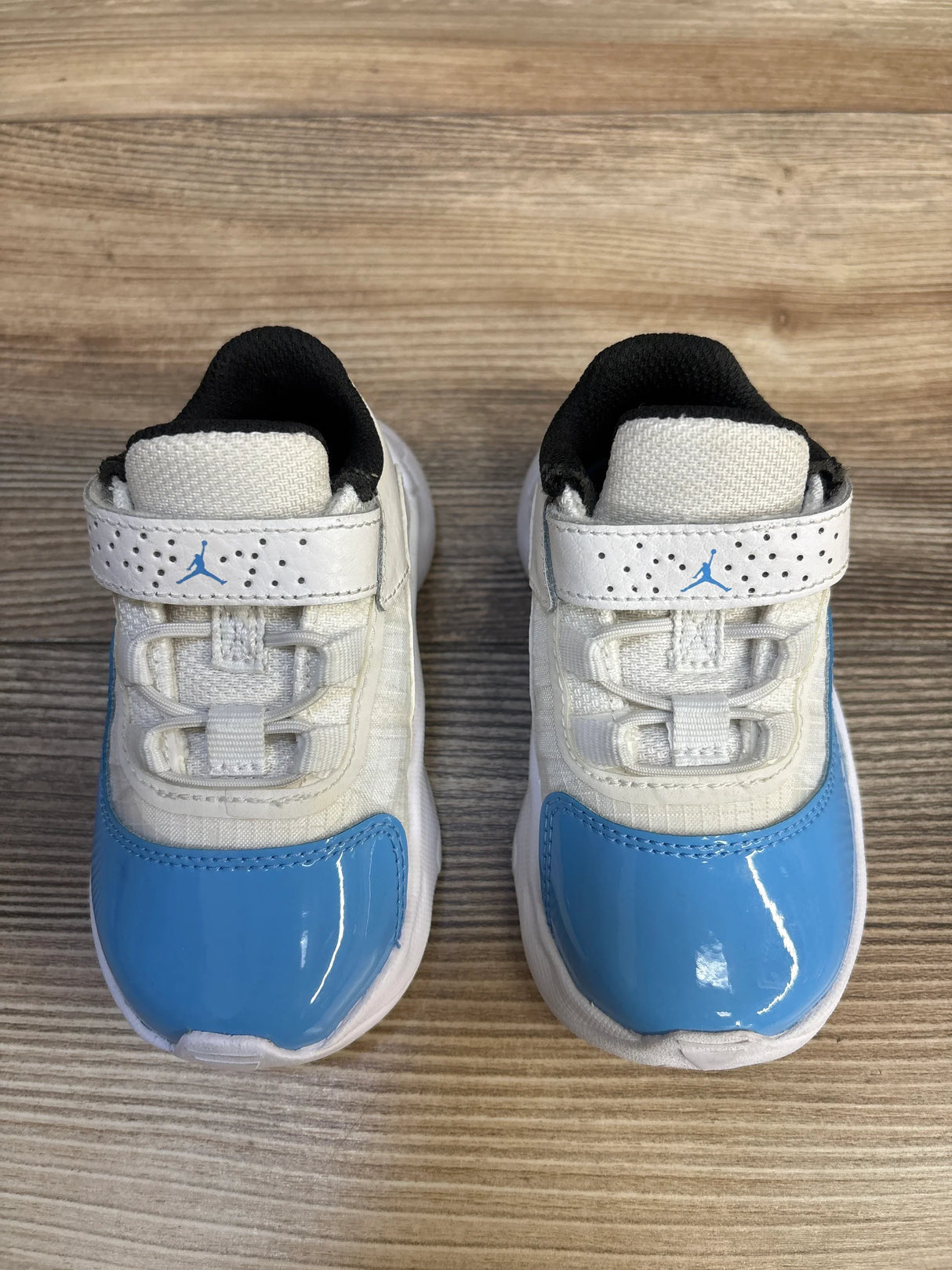 Baby blue and white sneakers with Velcro straps on wooden background, kids athletic shoes