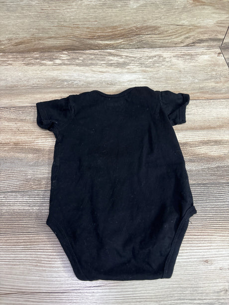 Back view of Disney The Lion King Brave Like Dad black bodysuit with short sleeves on a wood surface