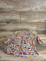 Flat lay of girls' long-sleeve floral dress (4T) showcasing gathered waist and long sleeves with elastic cuffs on a wood plank background